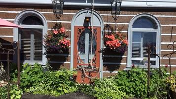 Un edificio con una puerta central, flanqueada por dos ventanas con jardineras.