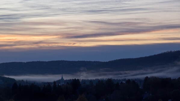A landscape with a church on a hill, surrounded by trees and fog. - Le Petit Clocher Gîte Touristique B&B (Saint-Sauveur)