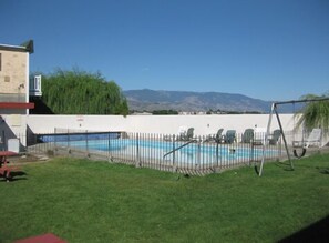 Un jardin avec une piscine, une balançoire et une vue sur les montagnes.