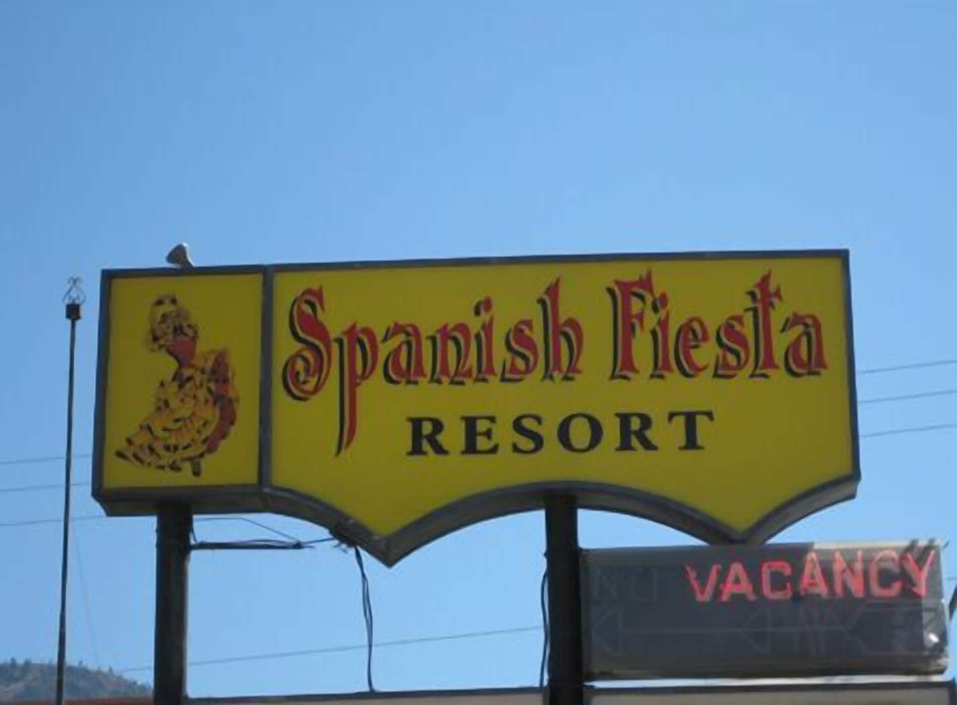 A sign for Spanish Fiesta Resort with a rooster emblem and a vacancy sign.