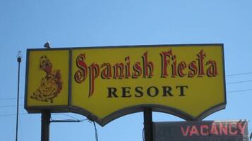 A sign for Spanish Fiesta Resort with a rooster emblem and a vacancy sign.