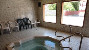 A room with a hot tub, tiled floor, and plastic chairs. - Falcon Resort (Osoyoos)