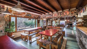 A rustic interior with wooden tables and benches, a stone wall, and a variety of wall decorations.