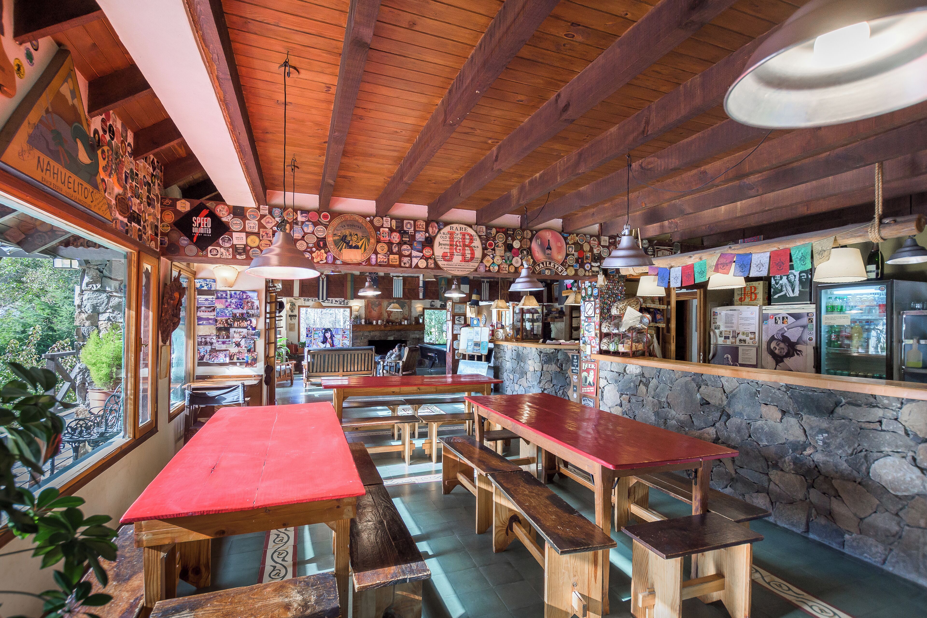 A rustic interior with wooden tables and benches, stone walls, and various memorabilia on the walls.