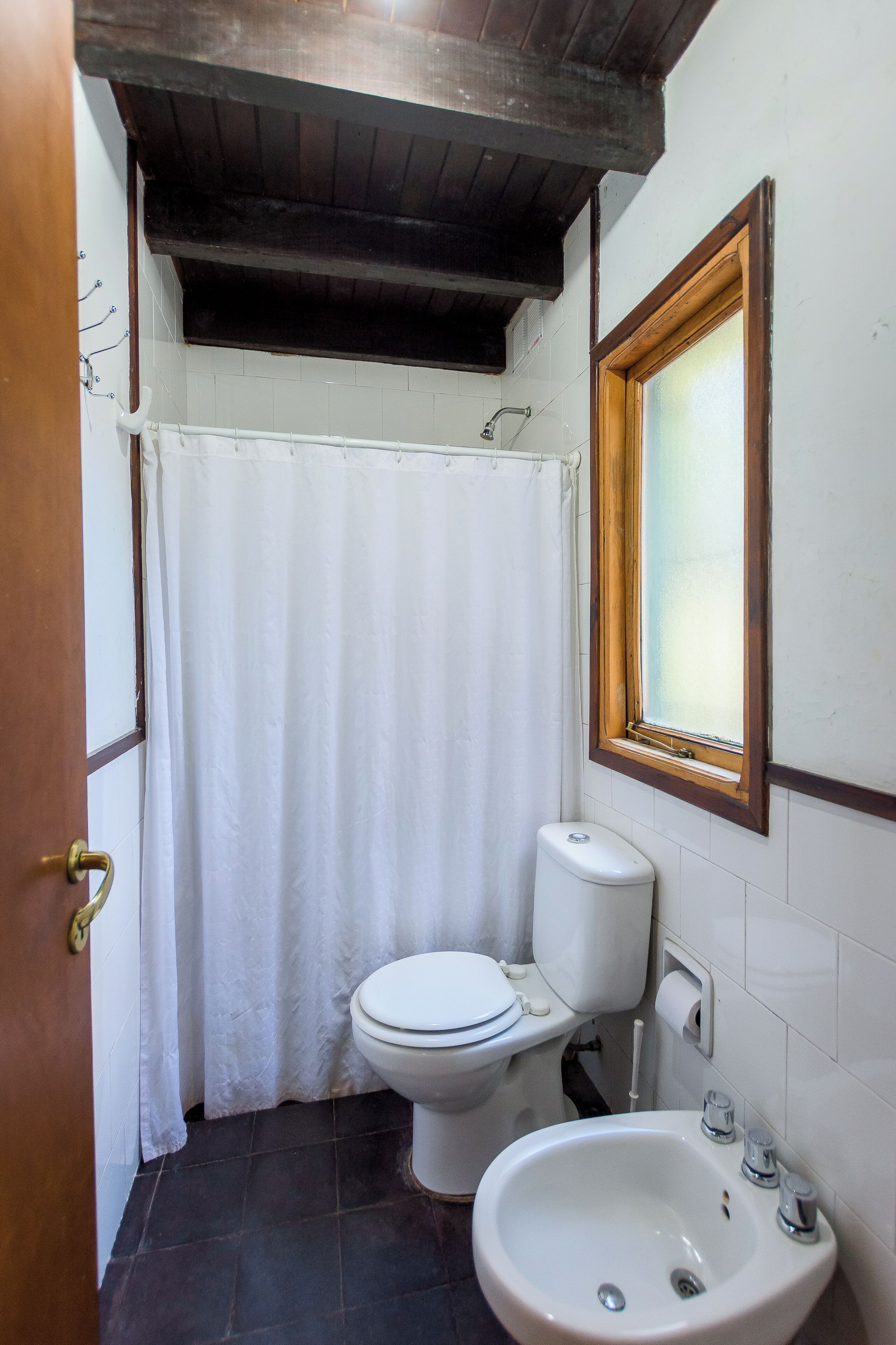 Un baño pequeño con inodoro, lavamanos y cortina de ducha.