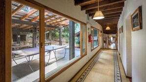 A corridor with wooden beams, large windows, and a tiled floor.