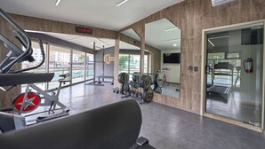 A gym with cardio equipment, weightlifting stations, and a digital display showing time. - Hotel Estancia Business Class (Guadalajara)