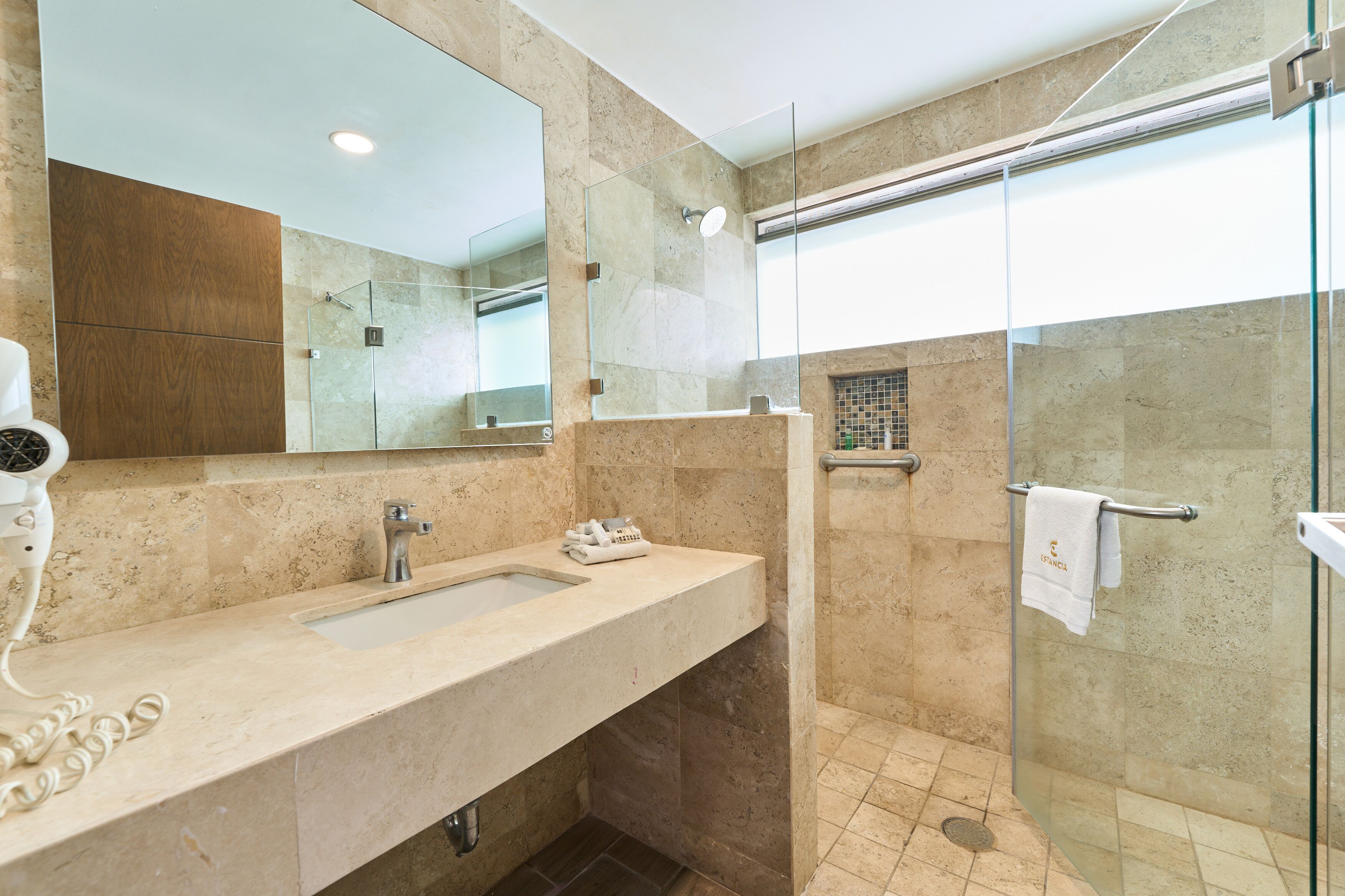 Un bagno moderno con uno specchio grande, un lavandino, una cabina doccia in vetro e un porta asciugamani.