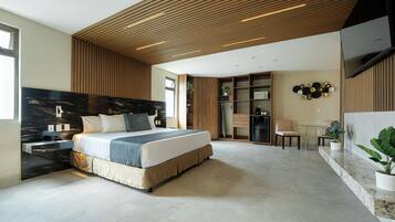 Een moderne slaapkamer met een groot bed, houten plafond, inbouwkasten en een zithoekje.