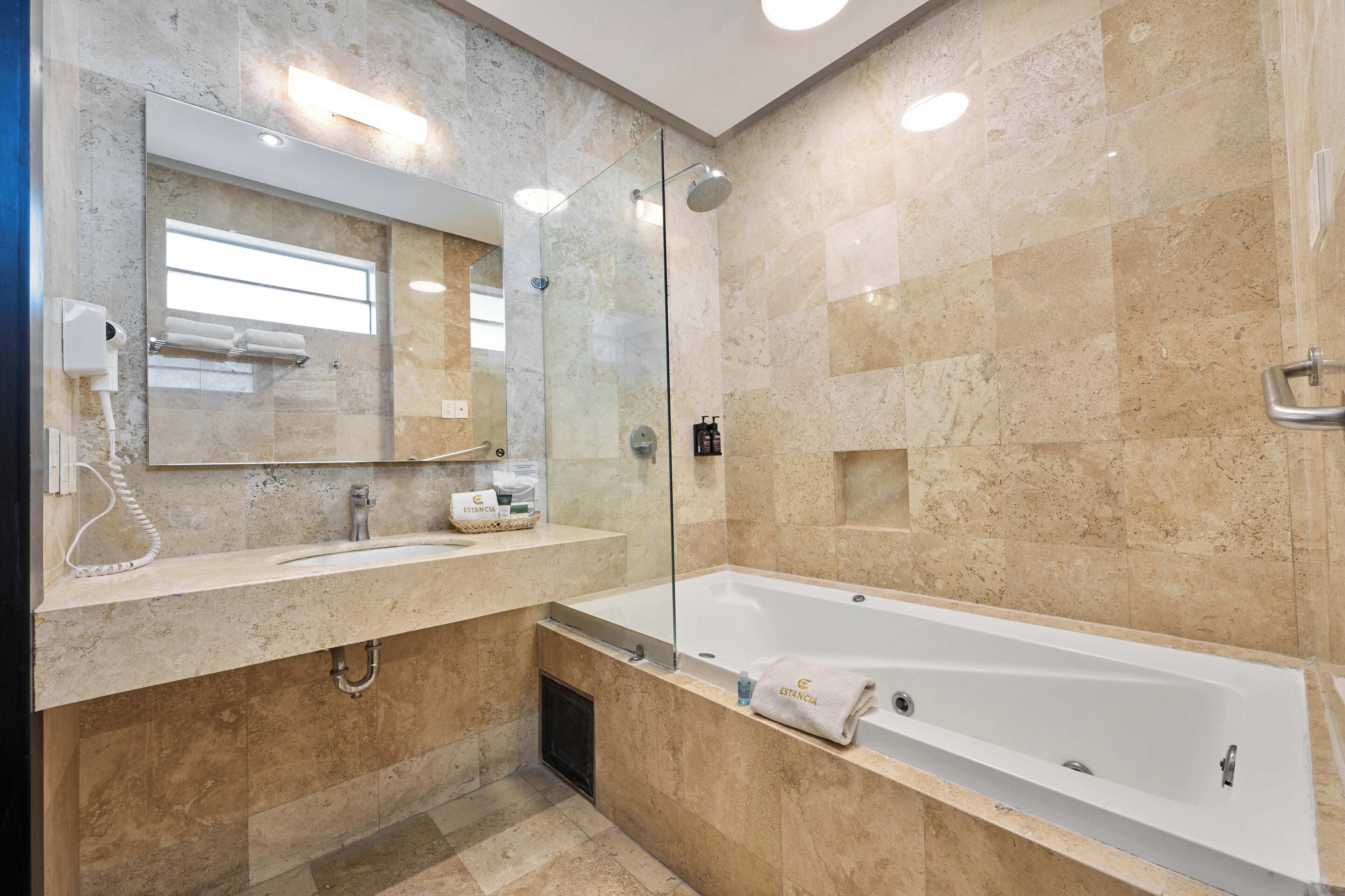 Une salle de bain moderne avec une douche à parois de verre, une grande baignoire et un meuble-lavabo avec un miroir.