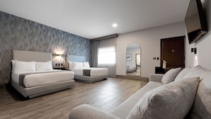 A modern hotel room with a large bed, a sofa, a TV, and a mirror. - Hotel Estancia Business Class (Guadalajara)