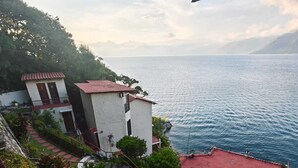 A coastal property with a red-roofed building, a garden with various plants, and a view of the sea. - Hotel La Villa de los Dioses (San Antonio Palopo)