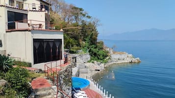 Una propiedad costera con piscina, terraza amueblada y vistas al mar y a las montañas.