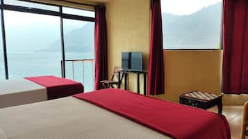 Habitación de hotel con dos camas, televisión, una mesita y vistas al mar y a las montañas.