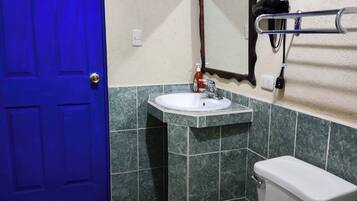 A bathroom with a blue door, a sink, a mirror, a towel rack, and a toilet.