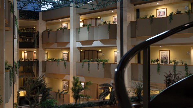 A multi-level hotel interior with balconies adorned with plants, framed artwork, and warm lighting. - Hotel Abastos Plaza (Mexico City)