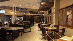 A restaurant with multiple tables and chairs, a bar area, and a signboard with menu items. - Hotel Abastos Plaza (Mexico City)