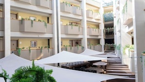 A multi-level hotel atrium with balconies, indoor plants, and a central staircase. - Hotel Abastos Plaza (Mexico City)