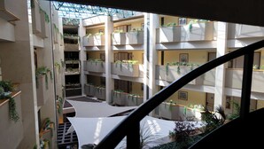 A multi-level atrium with balconies adorned with greenery, a central open space, and a staircase leading to upper floors. - Hotel Abastos Plaza (Mexico City)