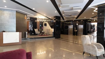 Un vestíbulo moderno con mostrador de recepción, zona de estar y escalera que conduce a un piso superior.