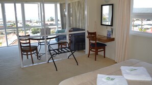 A hotel room with a balcony, a dining table, chairs, a bed, and a mirror. - The Menai Hotel Motel (South Burnie)