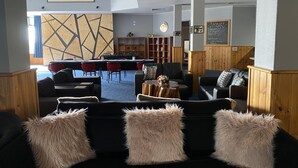 A modern lounge area with a central table, sofas, and a wooden partition. - The Menai Hotel Motel (South Burnie)