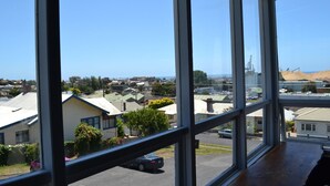 A view from a high-rise window overlooking a residential area with houses, a parking lot, and a distant industrial area. - The Menai Hotel Motel (South Burnie)