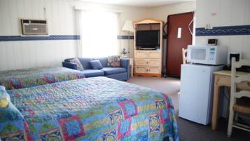A room with two beds, a TV, a microwave, and a dresser.