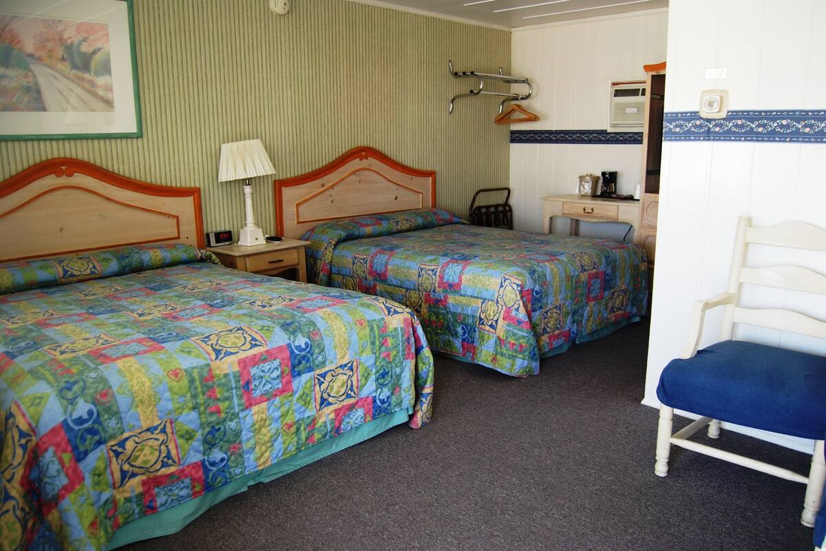 A room with two beds, a desk, and a chair.