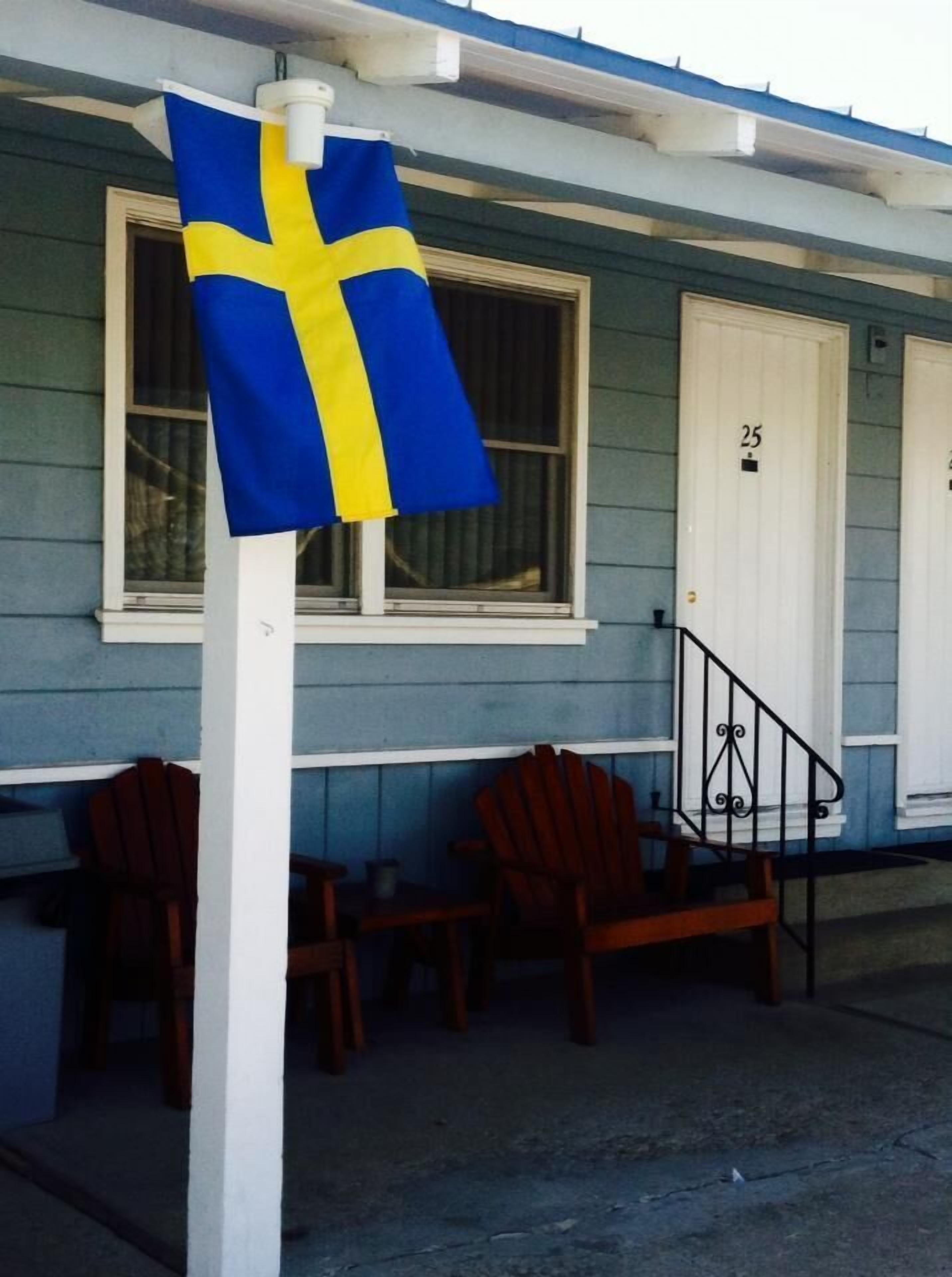 Un edificio con fachada azul, una puerta blanca con el número 25 y un asta con una bandera.