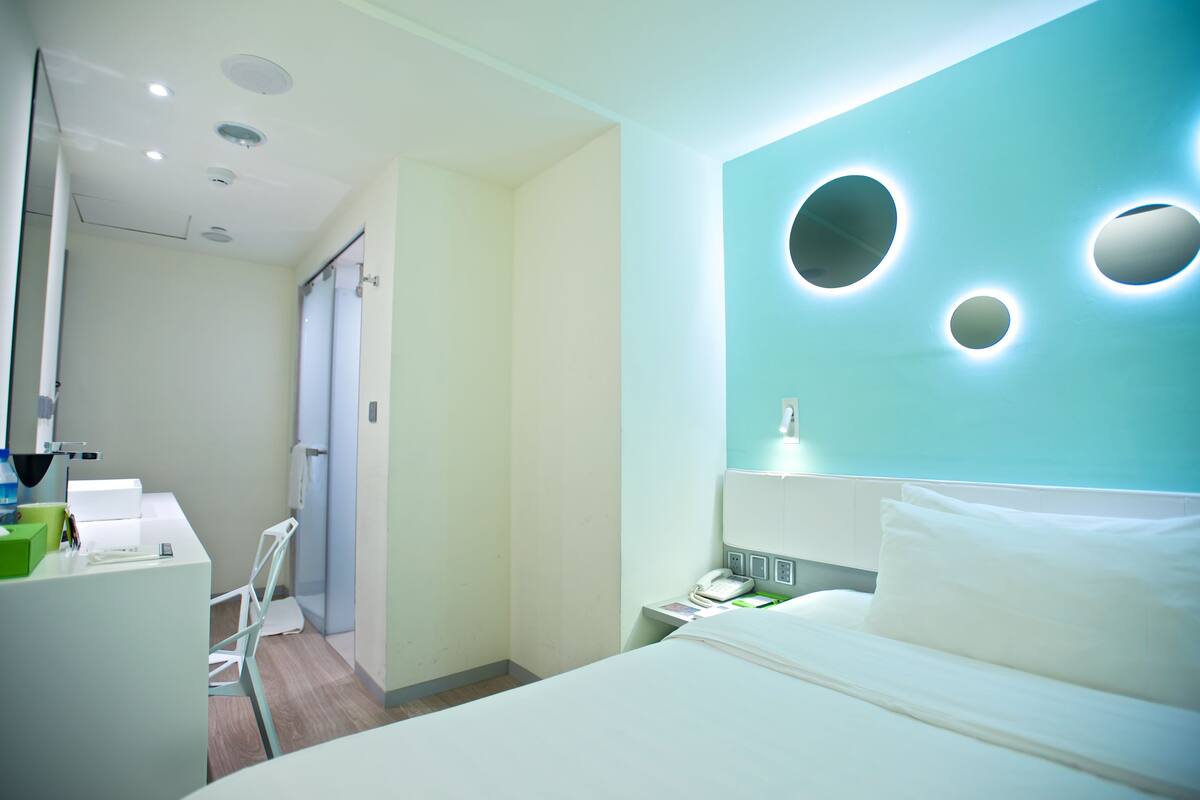 Ein Hotelzimmer mit einem Bett, einem Schreibtisch mit Telefon und einem Sessel.