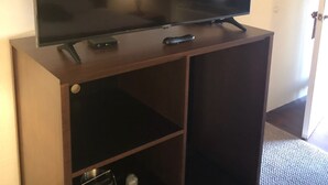 A flat-screen TV mounted on a wooden cabinet with a remote control and a lamp on the side. - Red Lion Inn & Suites La Pine (La Pine)