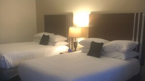 A hotel room with two beds, a nightstand with a lamp, and a wall-mounted clock. - Red Lion Inn & Suites La Pine (La Pine)
