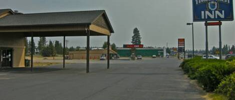 A parking lot with a Timbercrest Inn sign, a gas station, and a building with a covered entrance.