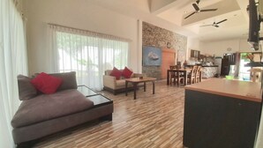 A modern living room with a sofa, coffee table, and dining area. - Samui Diving Resort (Koh Samui)