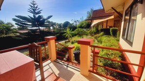 A balcony with a view of a garden and a building with a tiled roof. - Samui Diving Resort (Koh Samui)