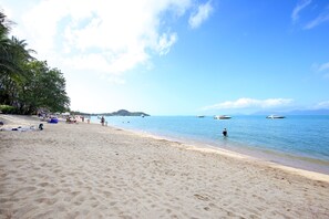 A sandy beach with clear blue water, boats, and a distant island. - Samui Diving Resort (Koh Samui)
