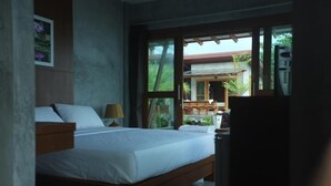 Un dormitorio con una cama grande, cabecera de madera y vistas a un espacio exterior a través de amplios ventanales.