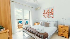 Ein Schlafzimmer mit einem Bett, einem Nachttisch, einem Schrank, einem Deckenventilator und Blick durch eine Glastür.