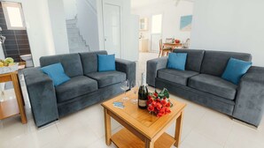 Ein modernes Wohnzimmer mit zwei grauen Sofas, einem Holztisch und einem Strauß roter Rosen.