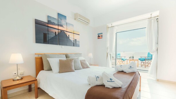 Ein Hotelzimmer mit Bett, Nachttisch, Fenster mit Blick und Bildern an der Wand.