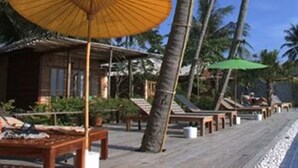 A wooden deck with lounge chairs and umbrellas, surrounded by palm trees. - Sunset Cove Resort (Ko Pha-ngan)