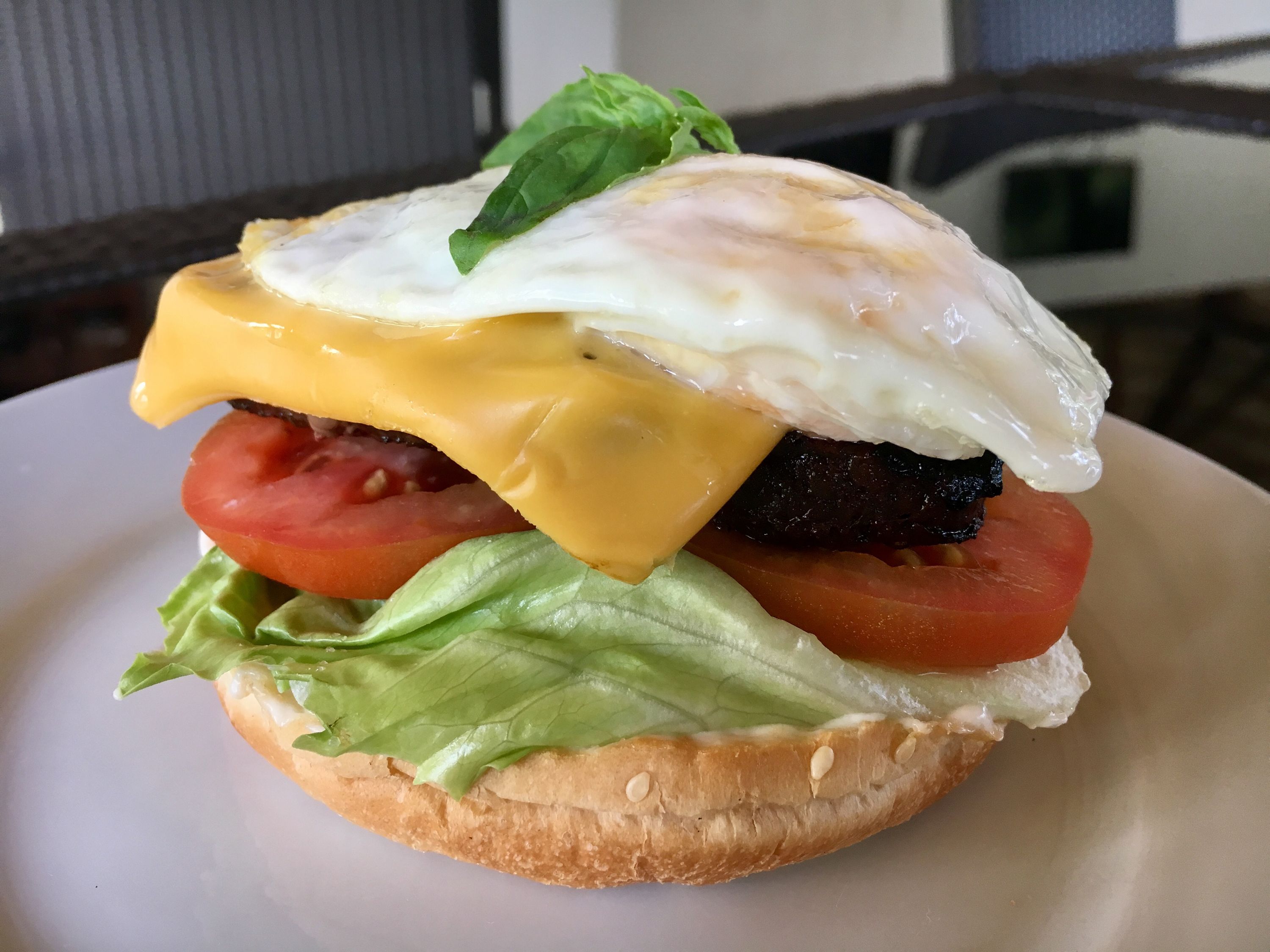 A sandwich with lettuce, tomato, egg, and cheese on a bun.
