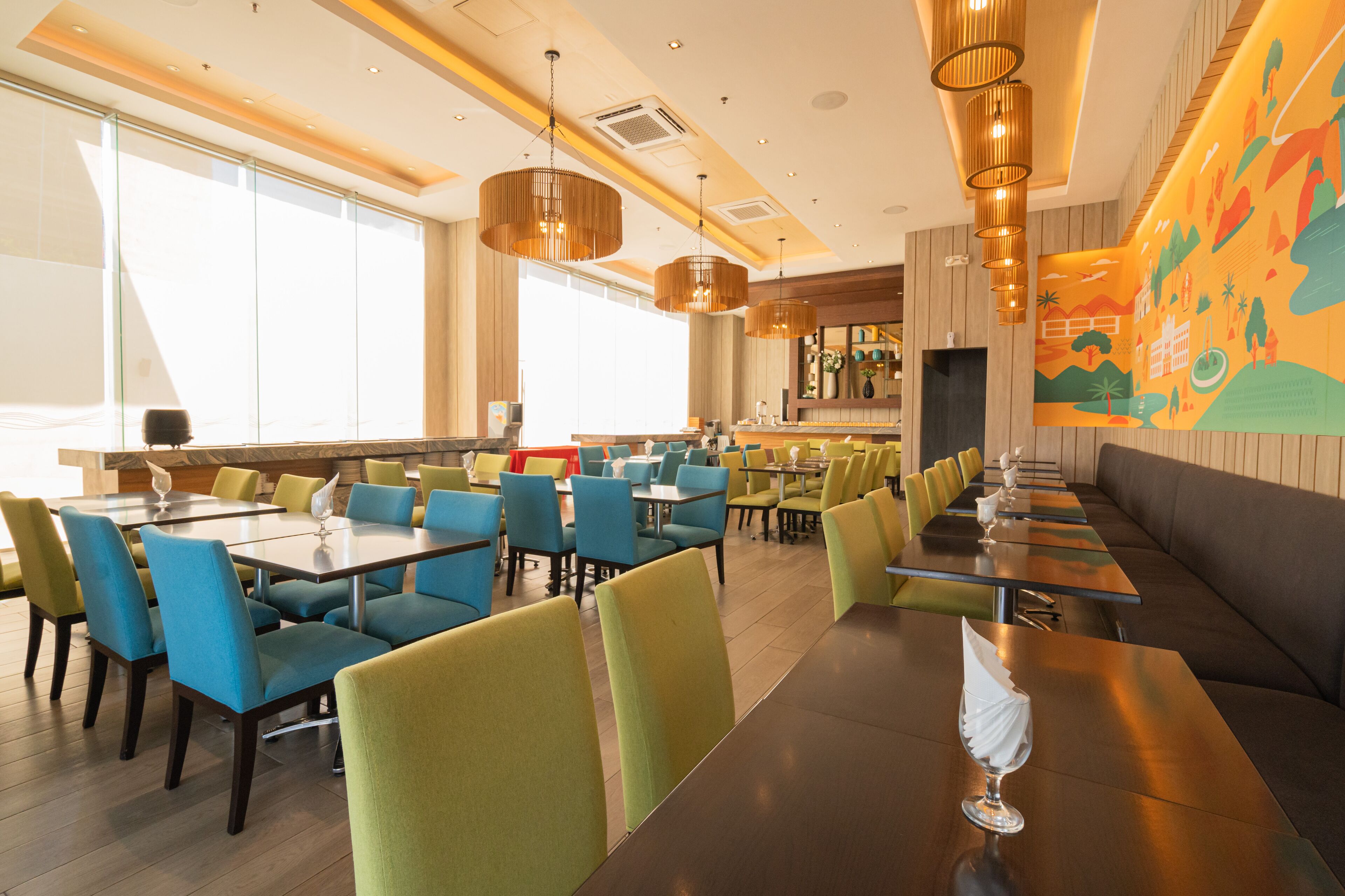Un restaurante moderno con mesas y sillas altas, una zona de bar y un mural en la pared.