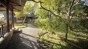 A covered walkway with a gravel path, surrounded by lush greenery and trees. - Cat Tien Farm Stay (Nam Cat Tien)