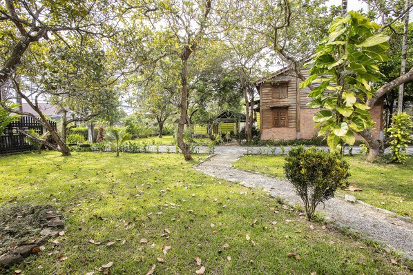 A garden with a pathway leading to a building with a brick facade and a green roof. - Cat Tien Farm Stay (Nam Cat Tien)