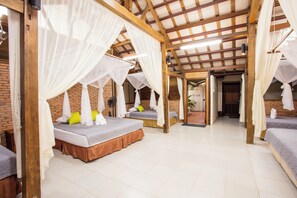 A room with four beds, each with a canopy, and a brick wall. - Cat Tien Farm Stay (Nam Cat Tien)