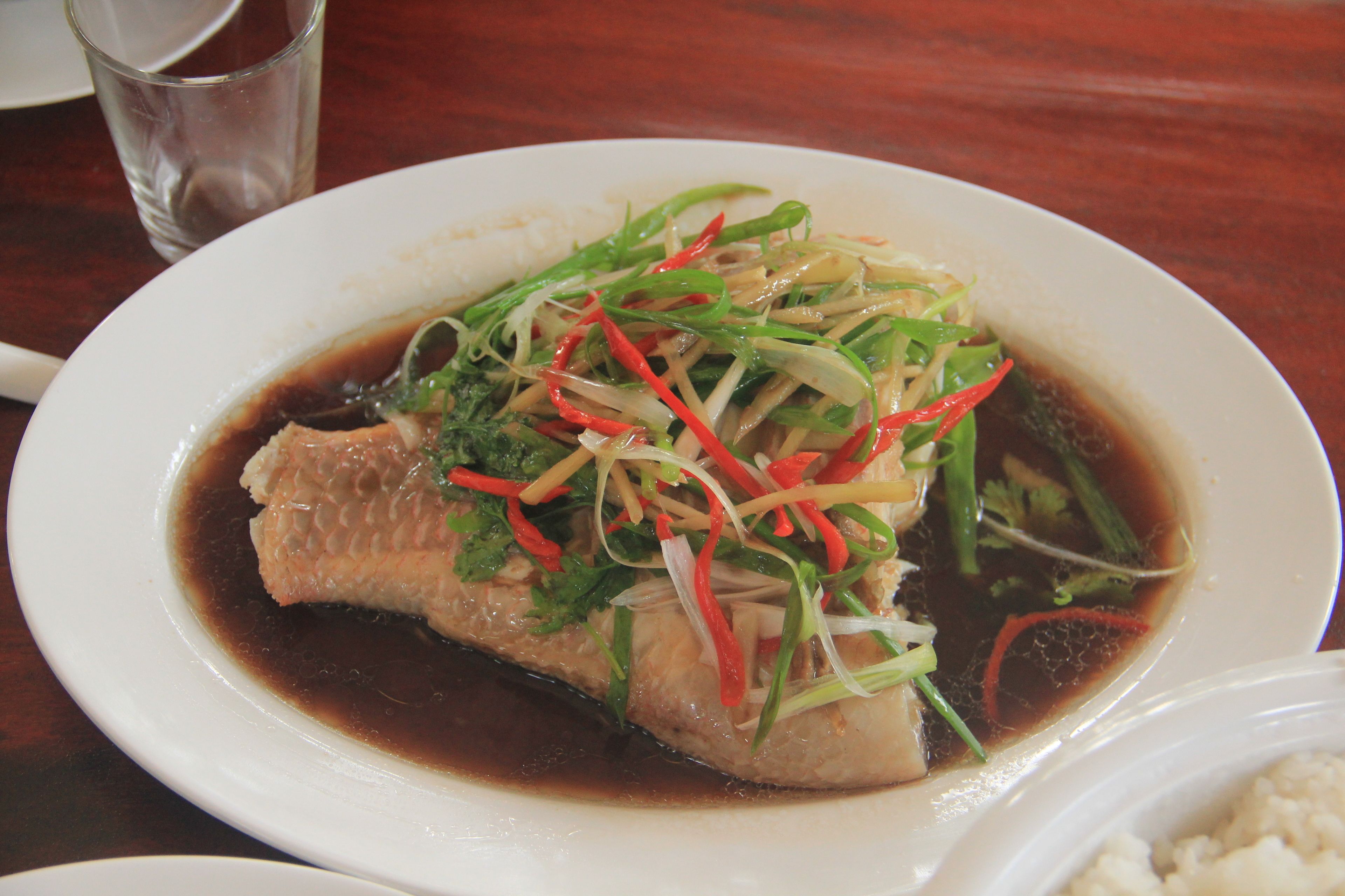 A plate of fish with vegetables and sauce.