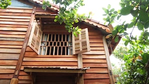 A wooden building with a balcony and a window with shutters. - Cat Tien Farm Stay (Nam Cat Tien)
