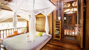 A room with a bed under a canopy, wooden flooring, and a view of the outside. - Cat Tien Farm Stay (Nam Cat Tien)